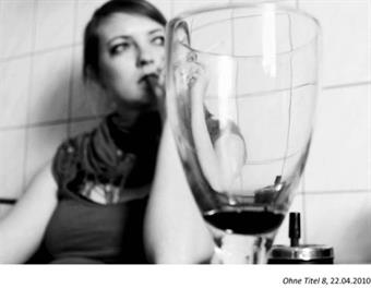 Masterthesis Foto schwarz-weiß, Glas Wein im Vordergrund, im Hintergrund verschwommen eine Frau 